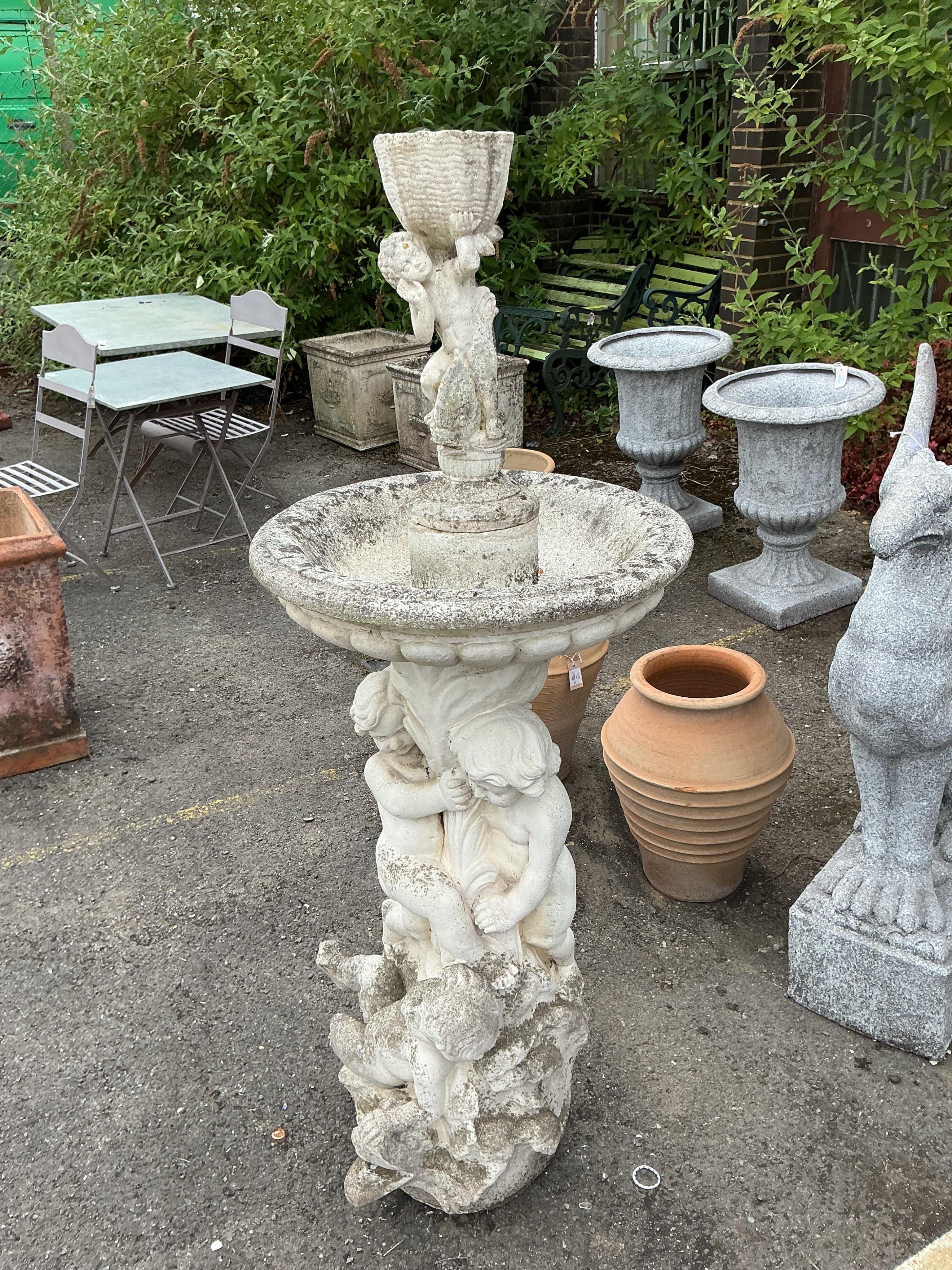 A reconstituted stone cherub and dolphin garden fountain, height 134cm